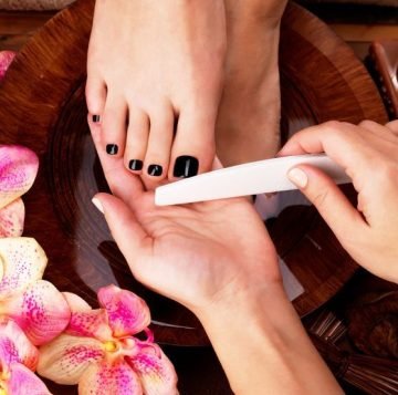 pedicurist master makes pedicure on woman's legs